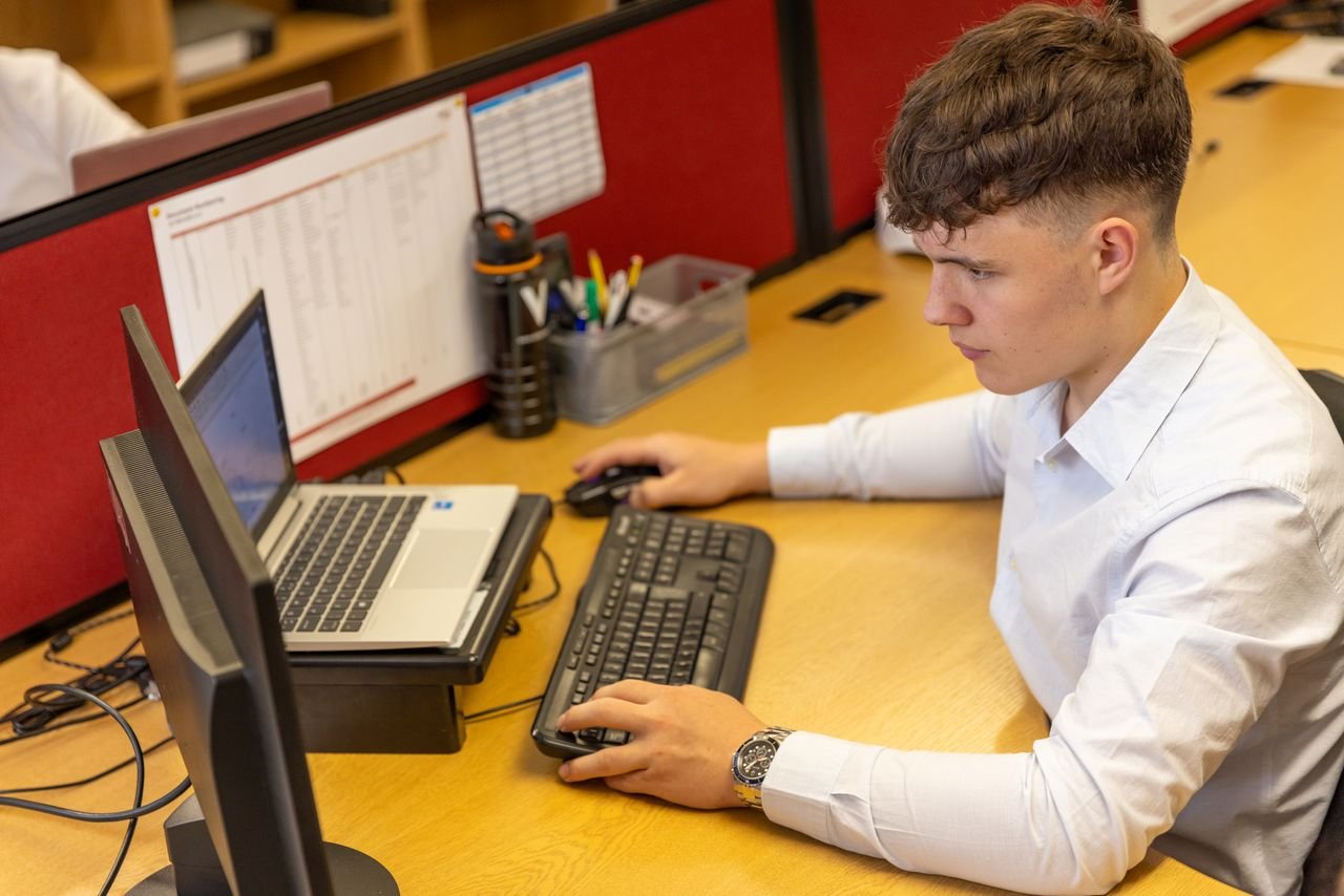Young male office worker engaged with computer tasks in a modern office setting.
